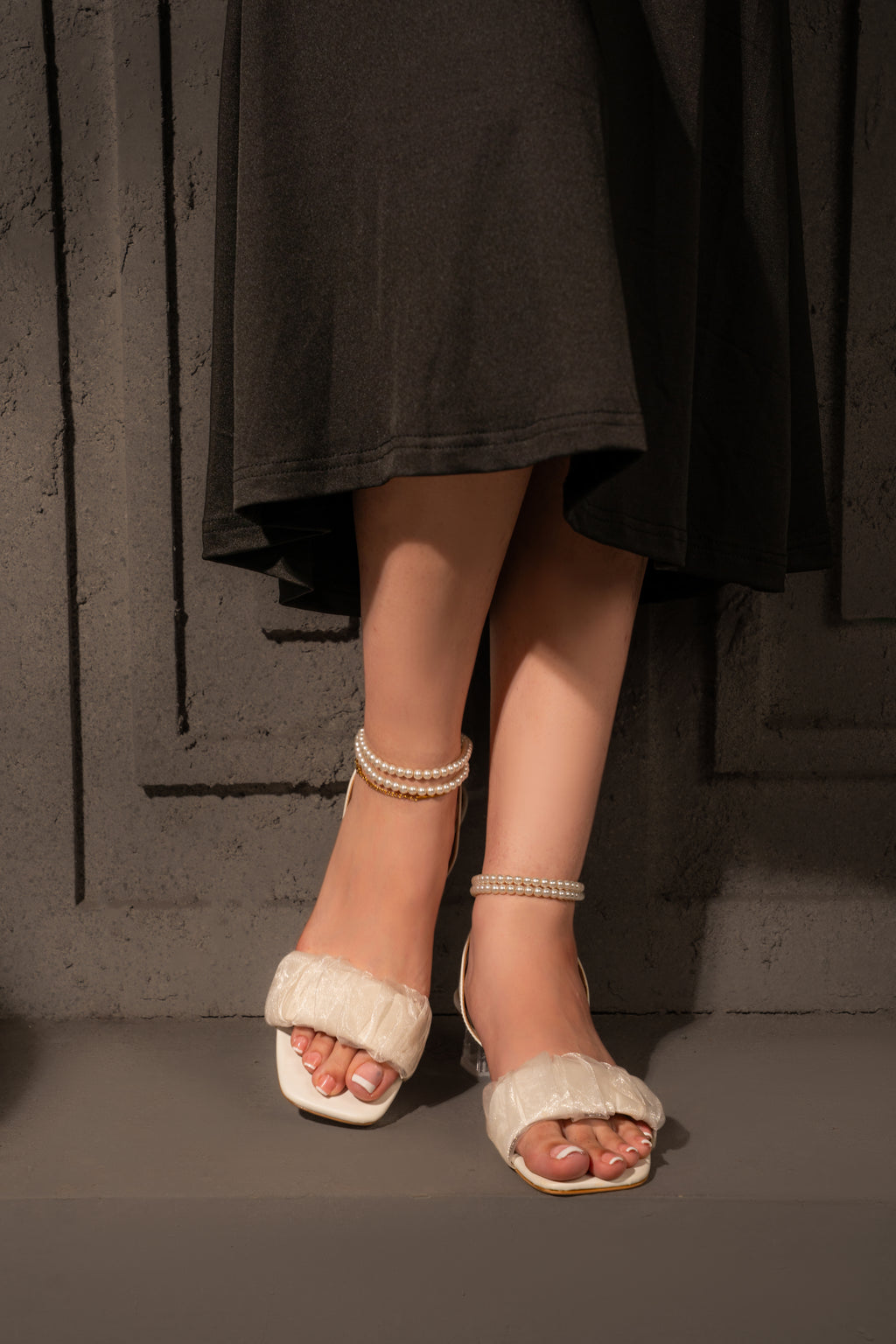 Front view of Meringue ivory sandals worn standing with black trousers