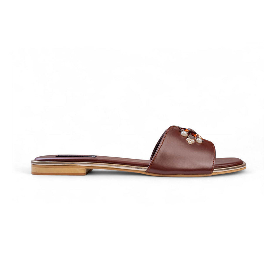 Side view of BLANEVE Cove brown flat slide with a wide strap and pearl and amber-toned embellishments.