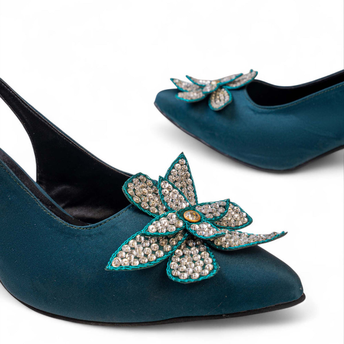 Close-up of the sequined floral embellishment with teal edging and a central gem on BLANEVE Lagoon heels.