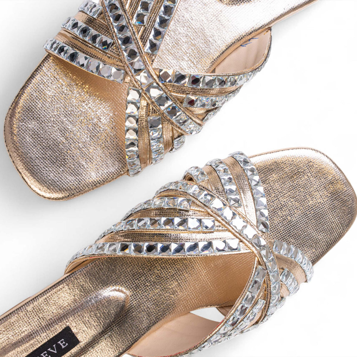 Close-up of faceted crystal embellishments on the gold-toned crisscross straps of BLANEVE Halo slides.