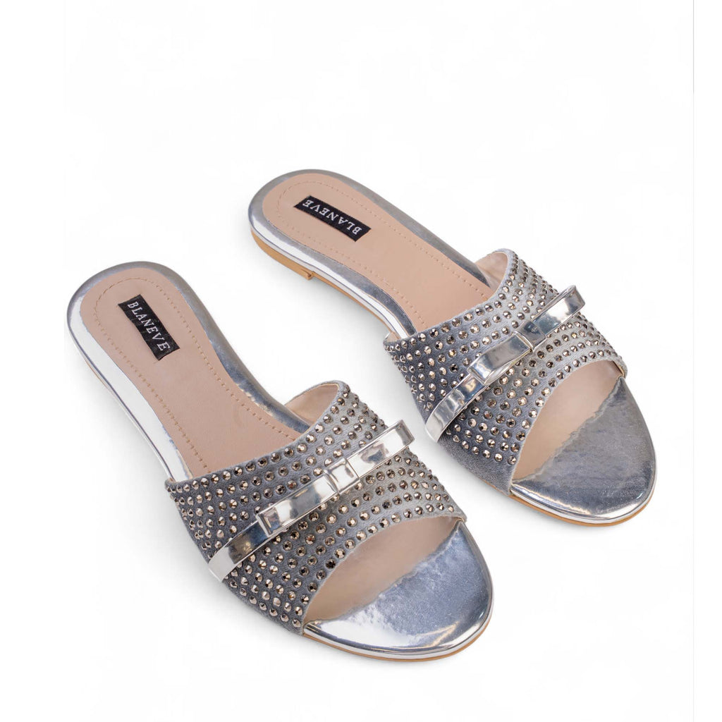 Pair of BLANEVE Starling silver-toned flat slides with wide embellished straps and reflective toe beds.