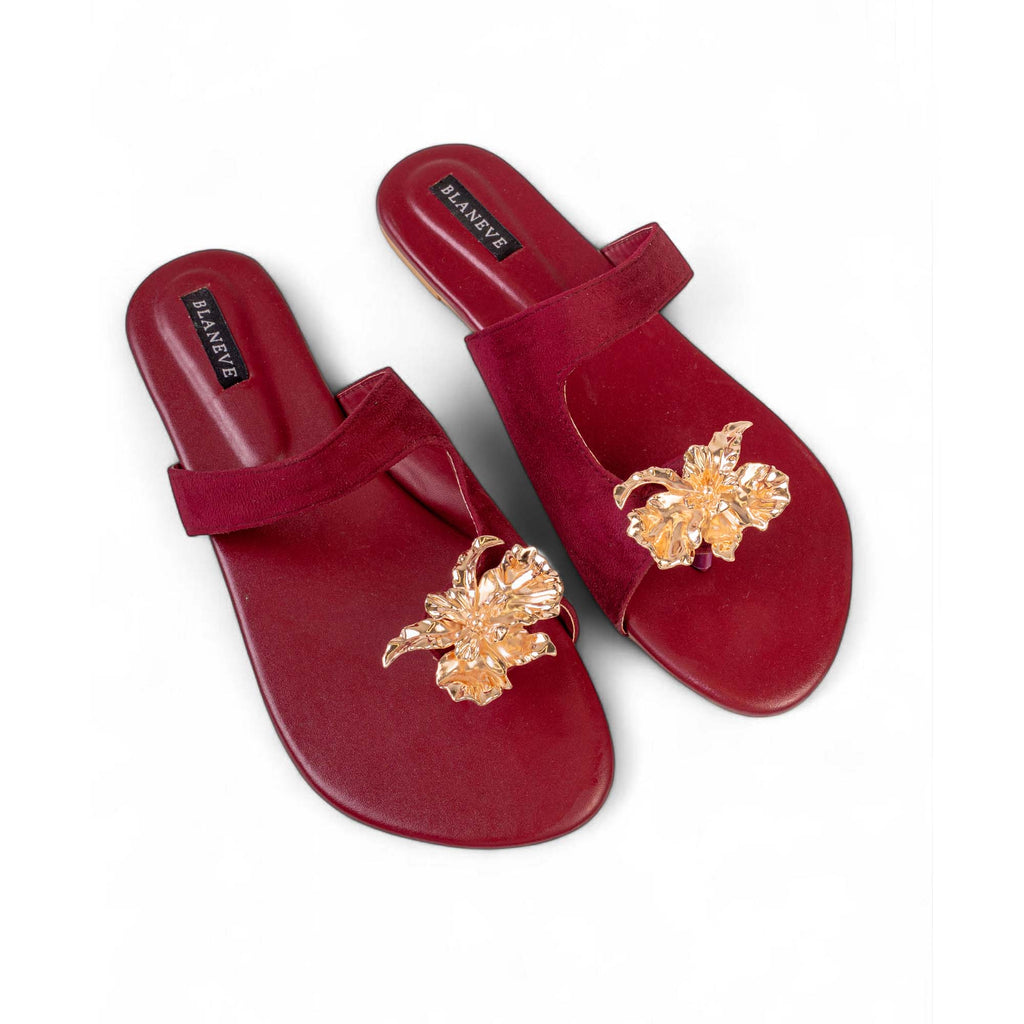 Pair of BLANEVE Merlot maroon flat sandals showing rounded open toes and sculpted gold-toned floral details